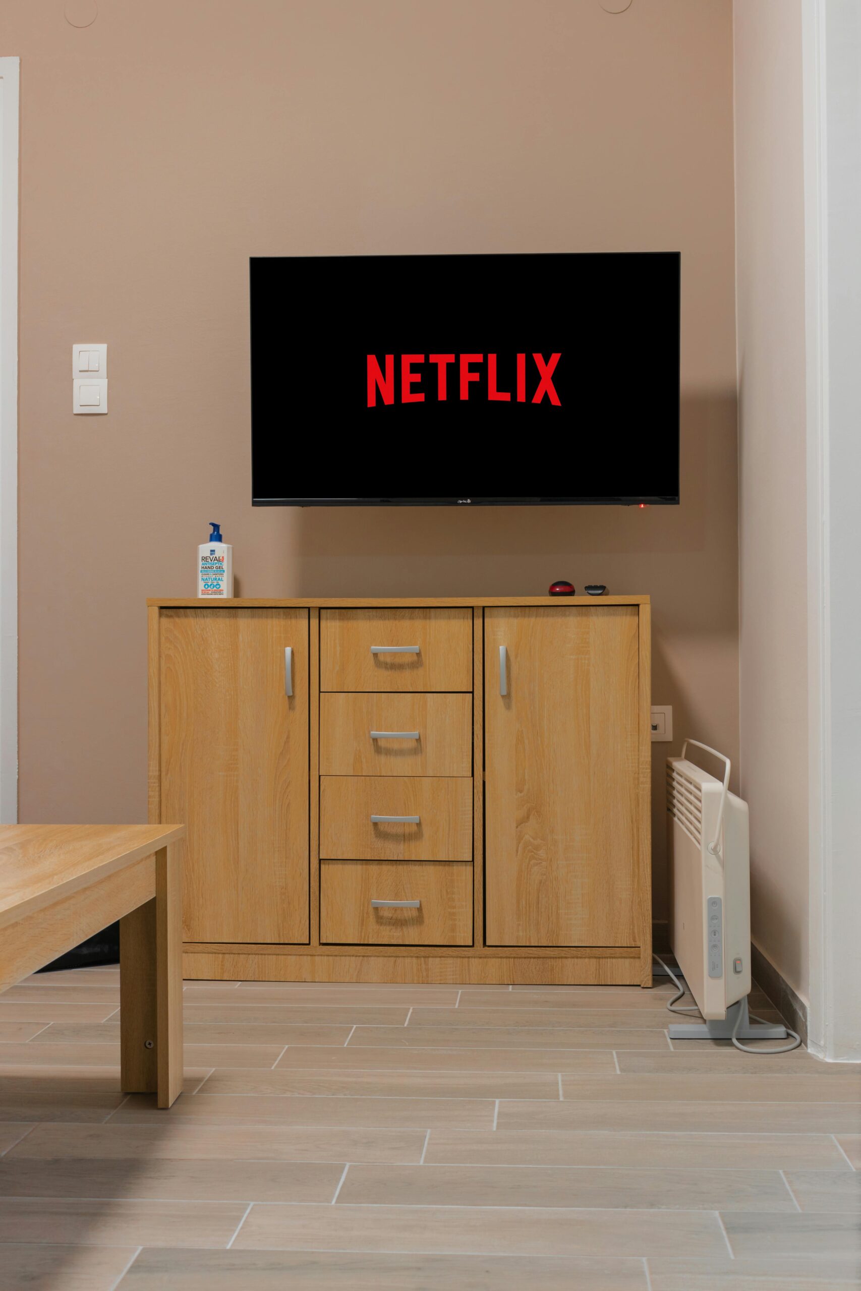 A cozy living room setup featuring a wall-mounted TV displaying Netflix above a wooden cabinet.